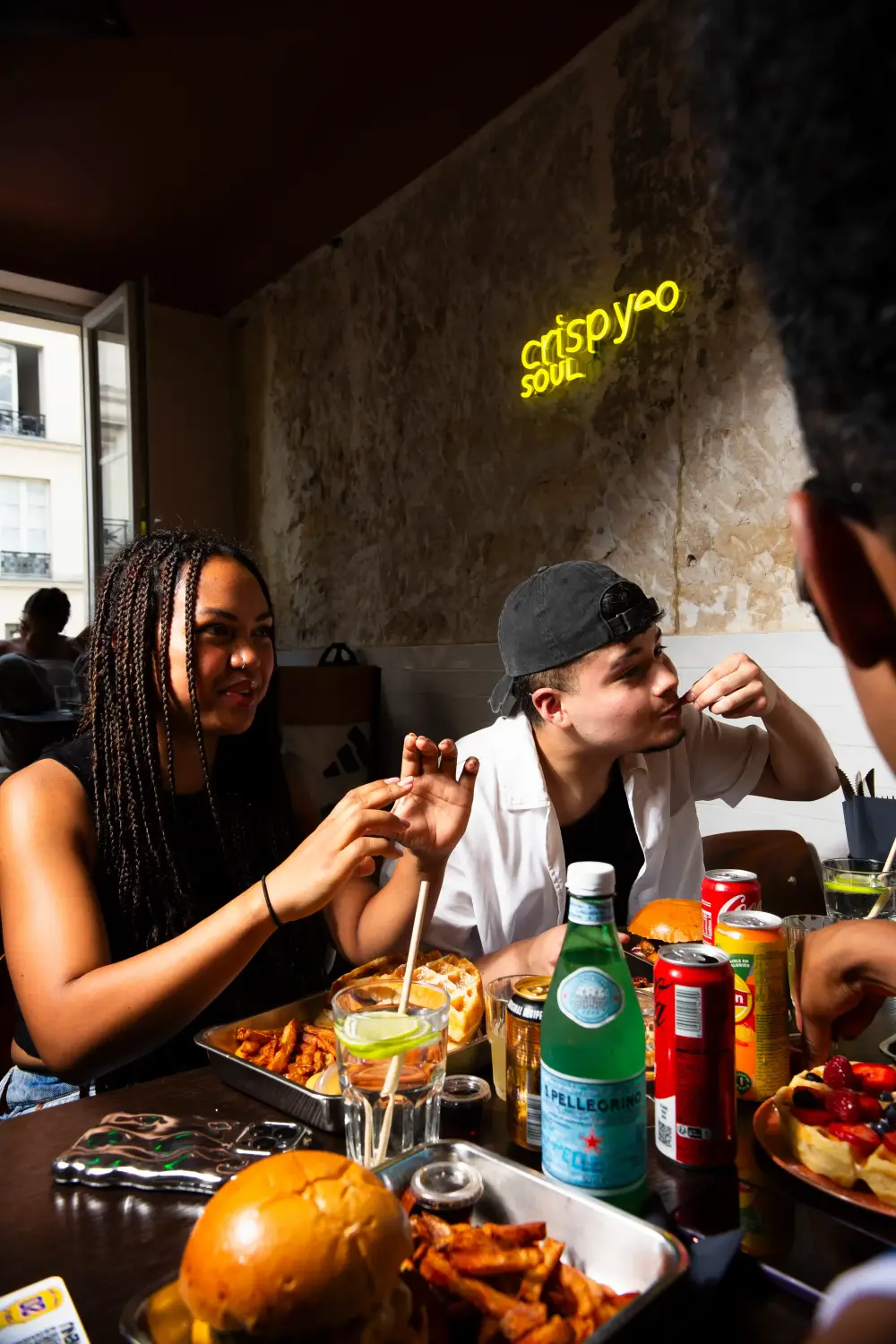 Amis attablés partageant burgers et frites chez CRISPY SOUL
